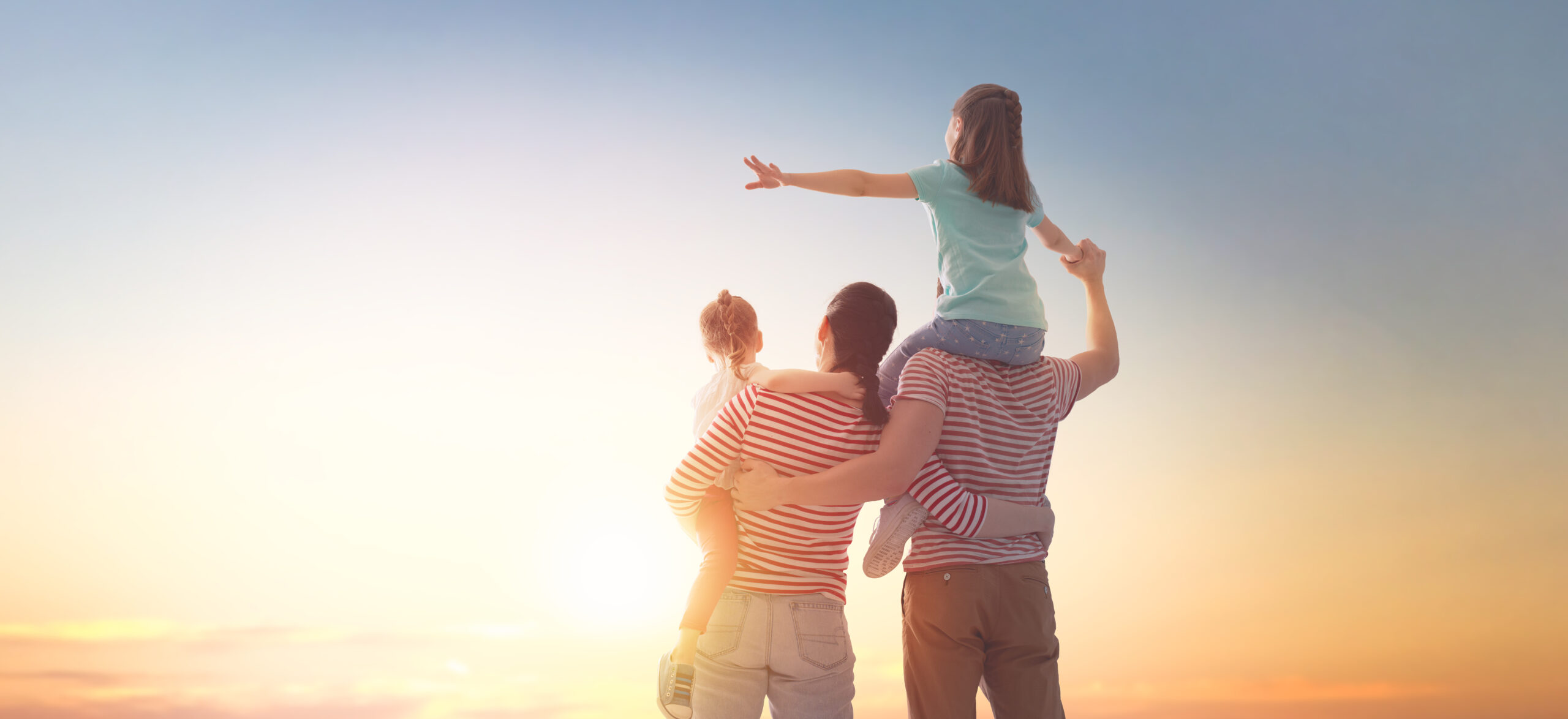 happy family at sunset. father, mother and two children daughters having fun and playing in nature. the child sits on the shoulders of his father.